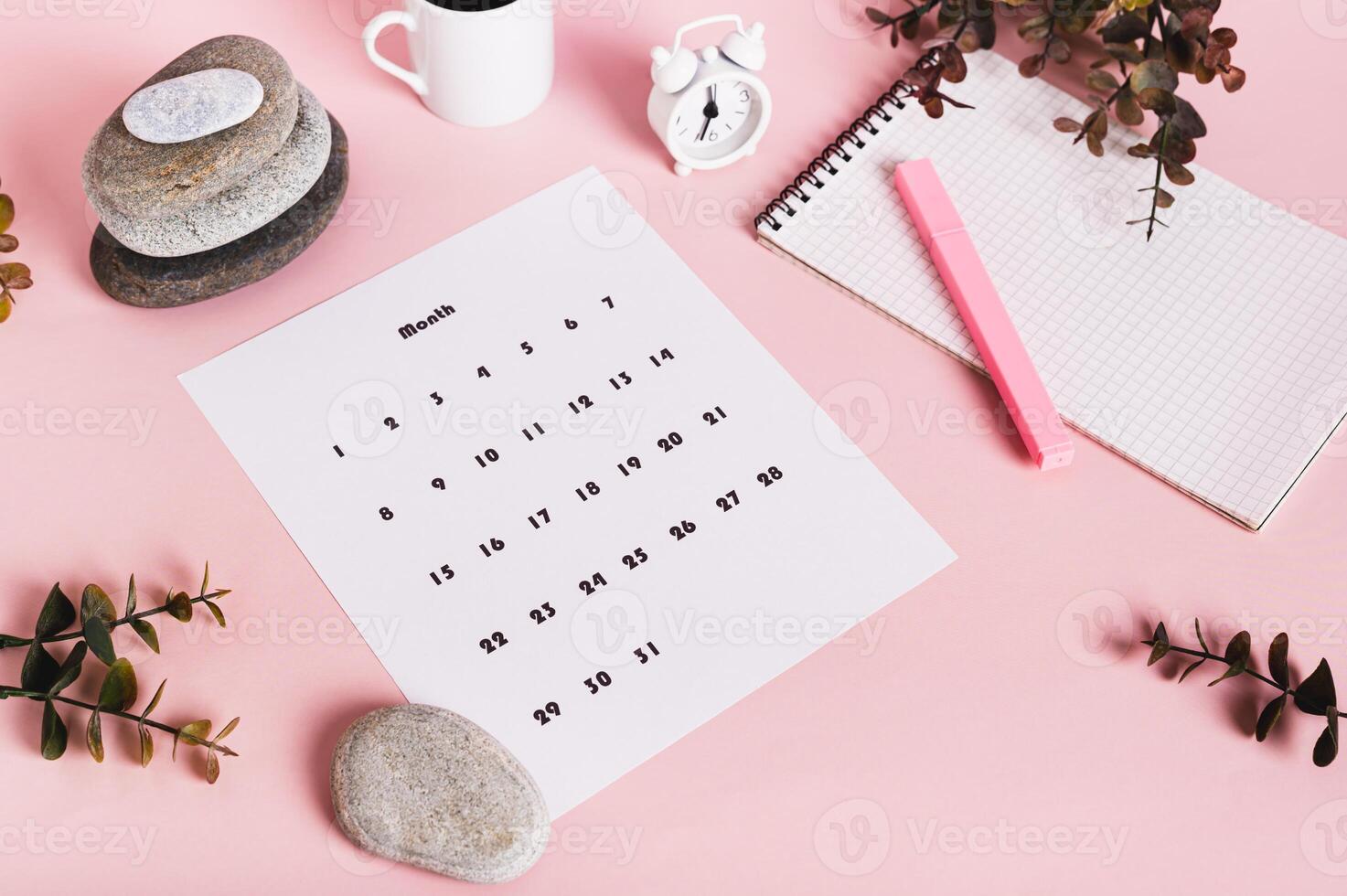 Calendar, alarm clock, notebook and pen on a pink background photo