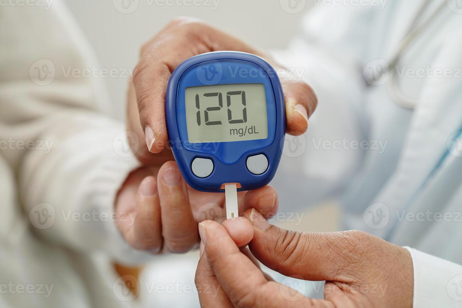 Asian doctor using digital glucose meter for check sample blood sugar level to treatment di photo