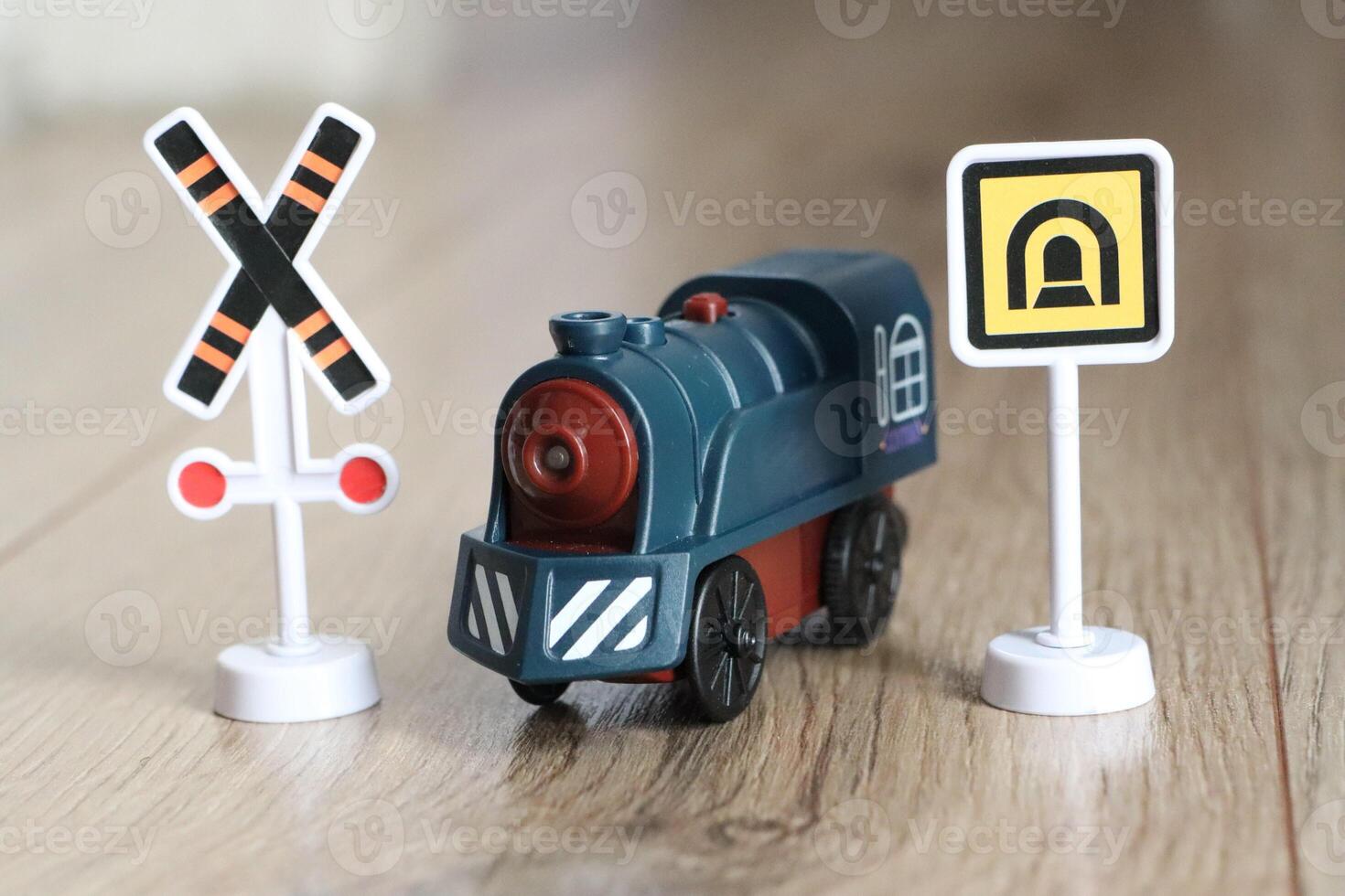 A Colorful Toy Train adorned with various Warning Signs meticulously placed on a Wooden Surface photo