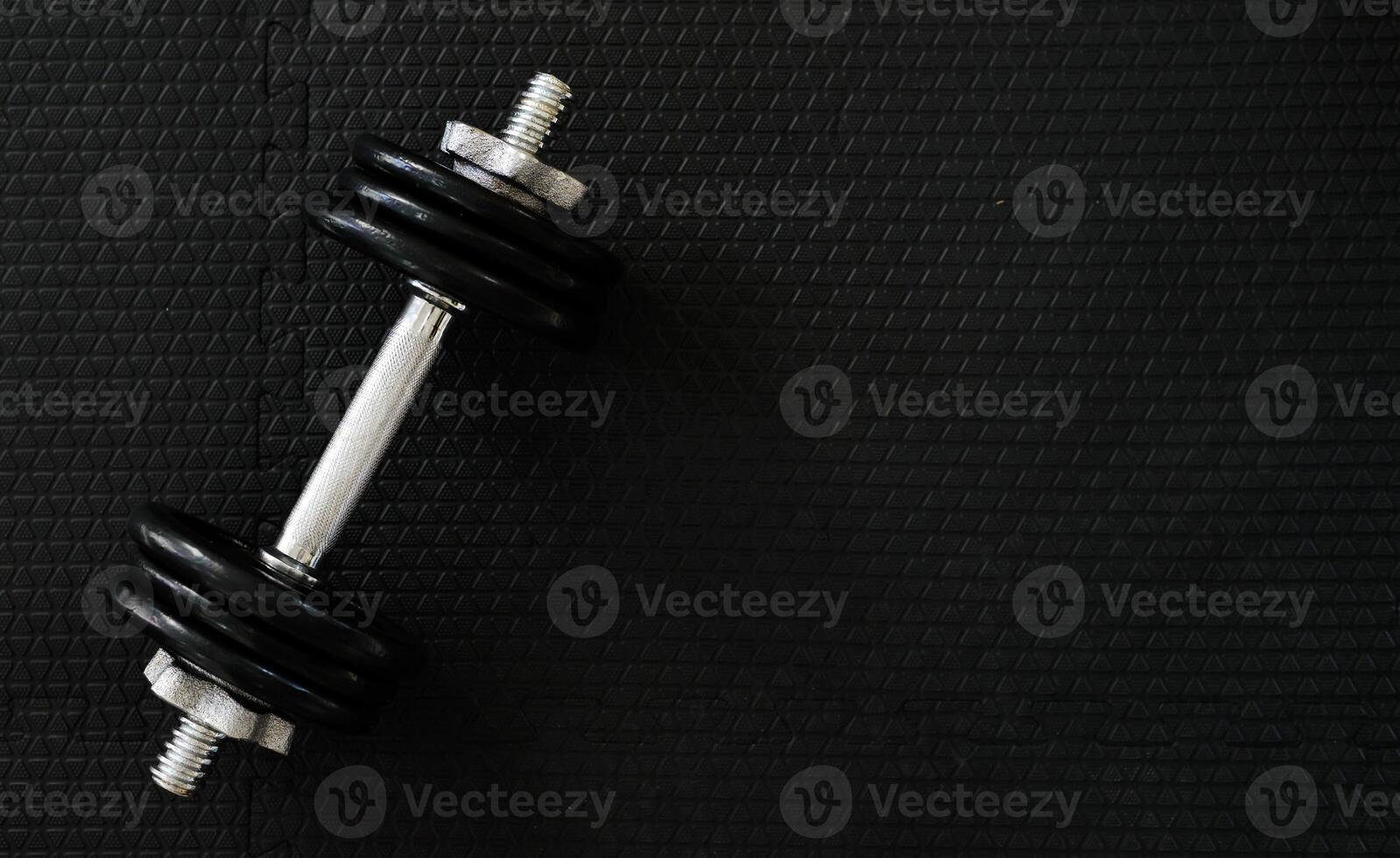 Top view of Iron dumbbells or weights on black floor with copy space for text on right photo