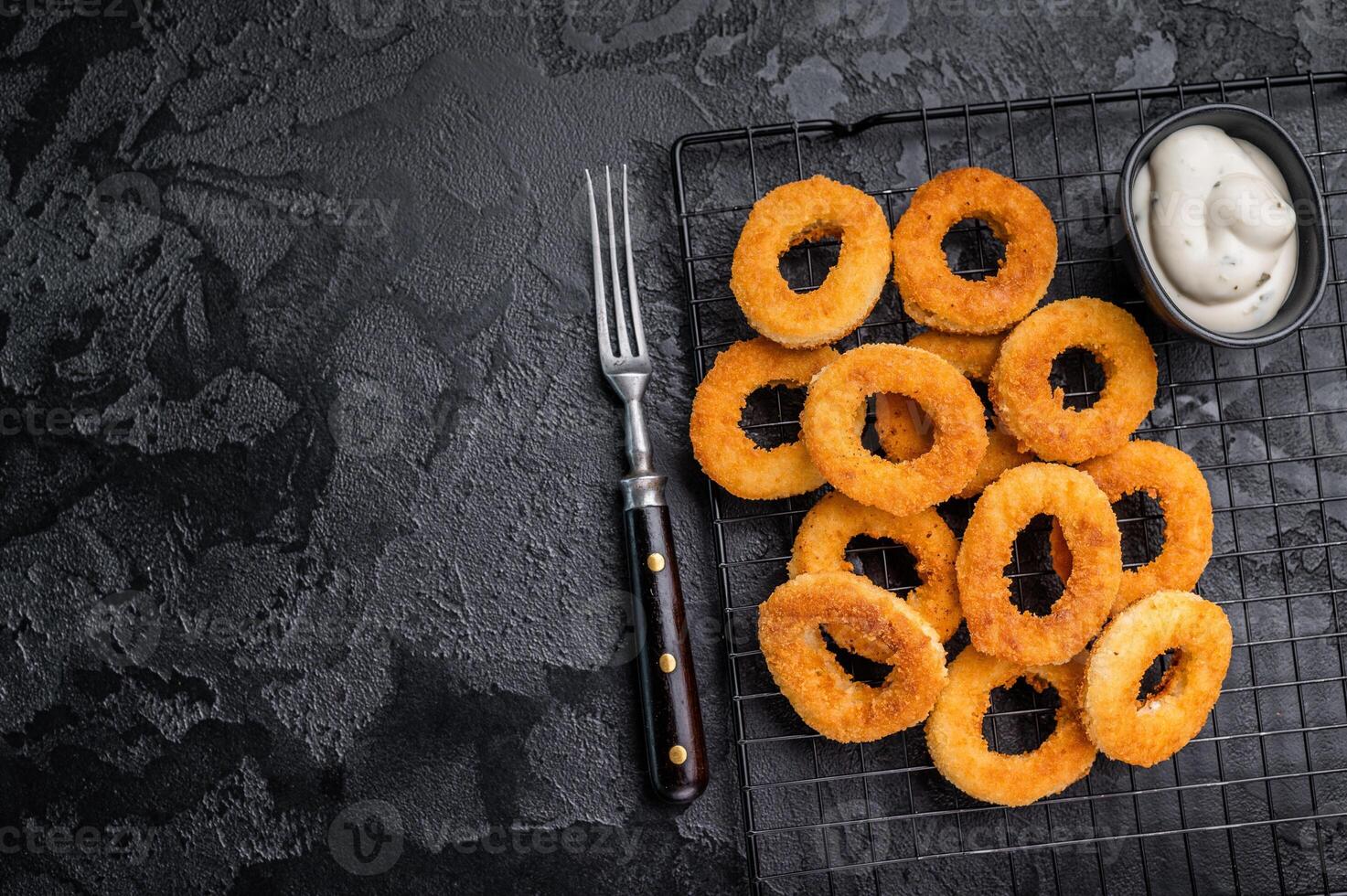 Ready or eat Deep Fried crunchy onion rings, delicious snack. black background. top view photo