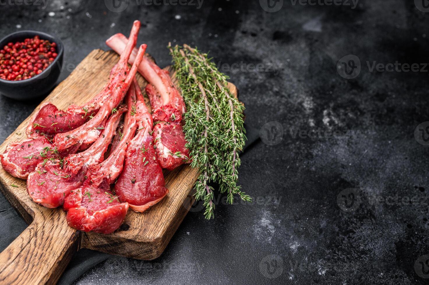 Raw mutton cutlets, fresh lamb meat chops on a wooden board. black background. top view photo