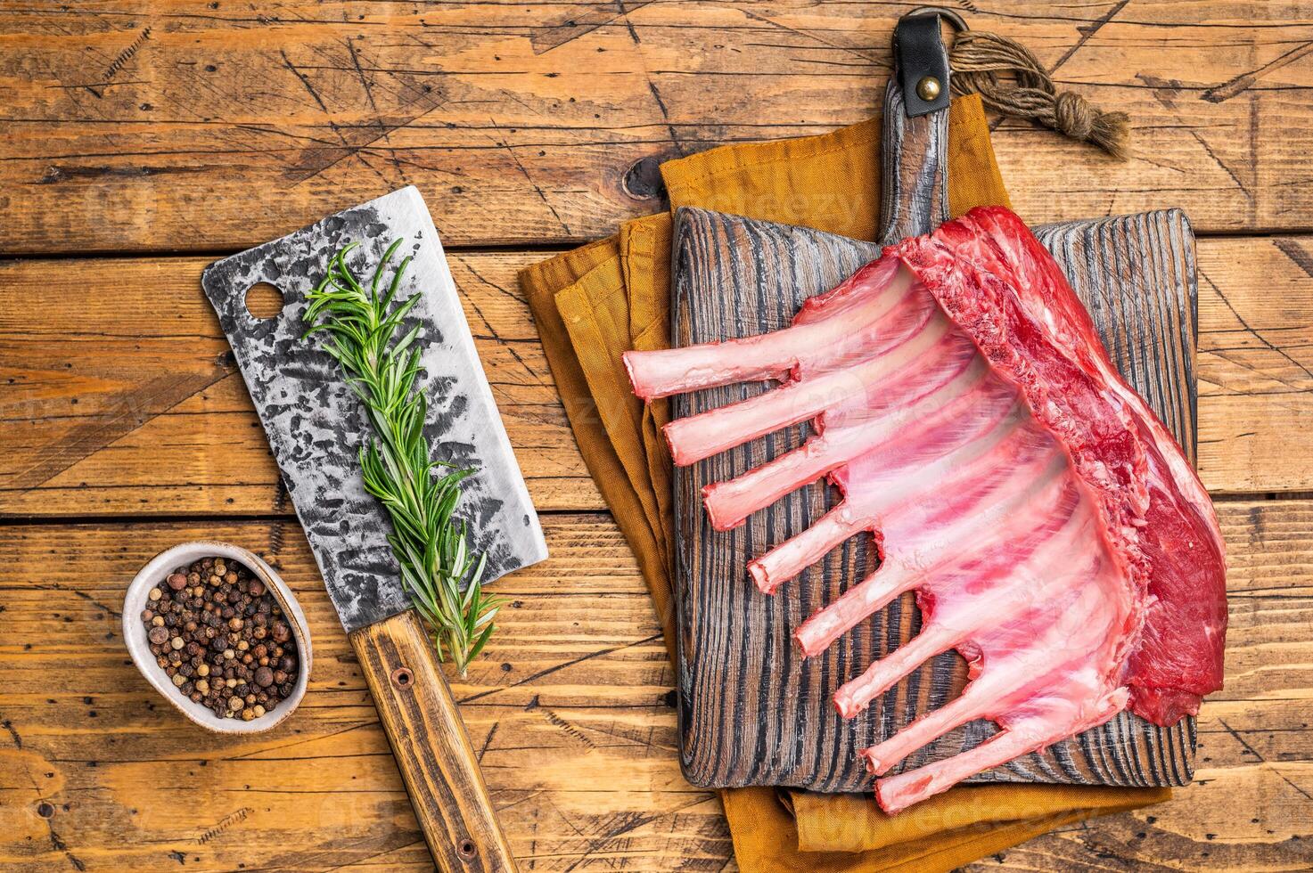 Butcher board with Raw lamb meat for chops steaks, fresh rack of mutton. wooden background. top view photo