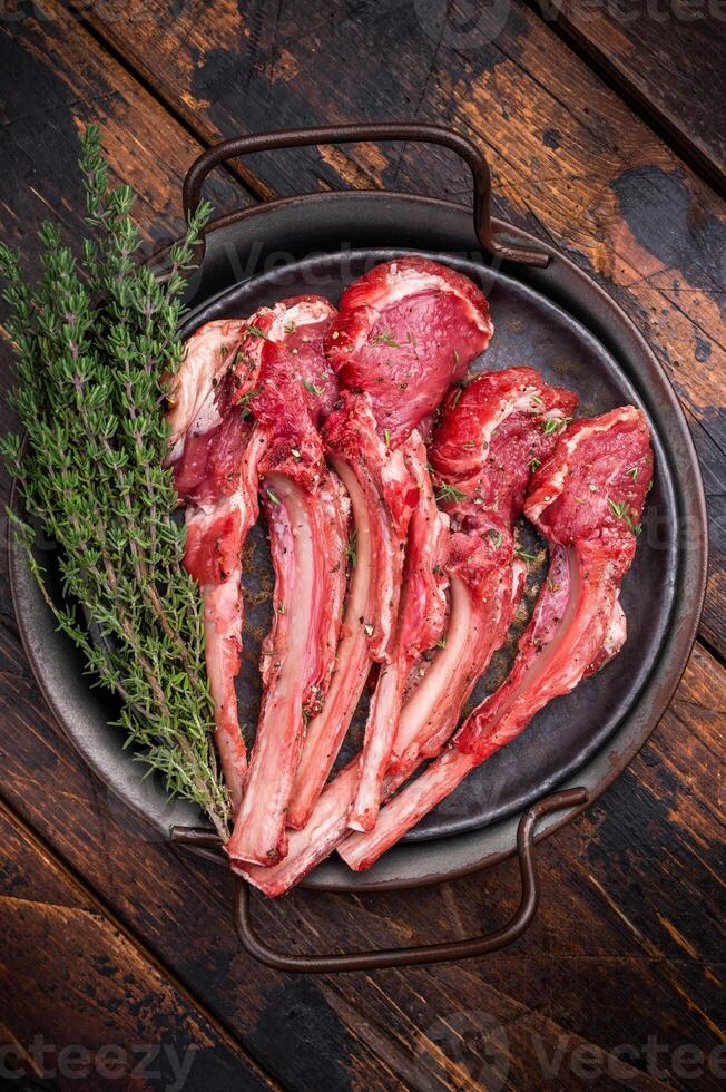 Raw lamb chop cutlets, fresh mutton meat for steaks with herbs. wooden background. top view photo