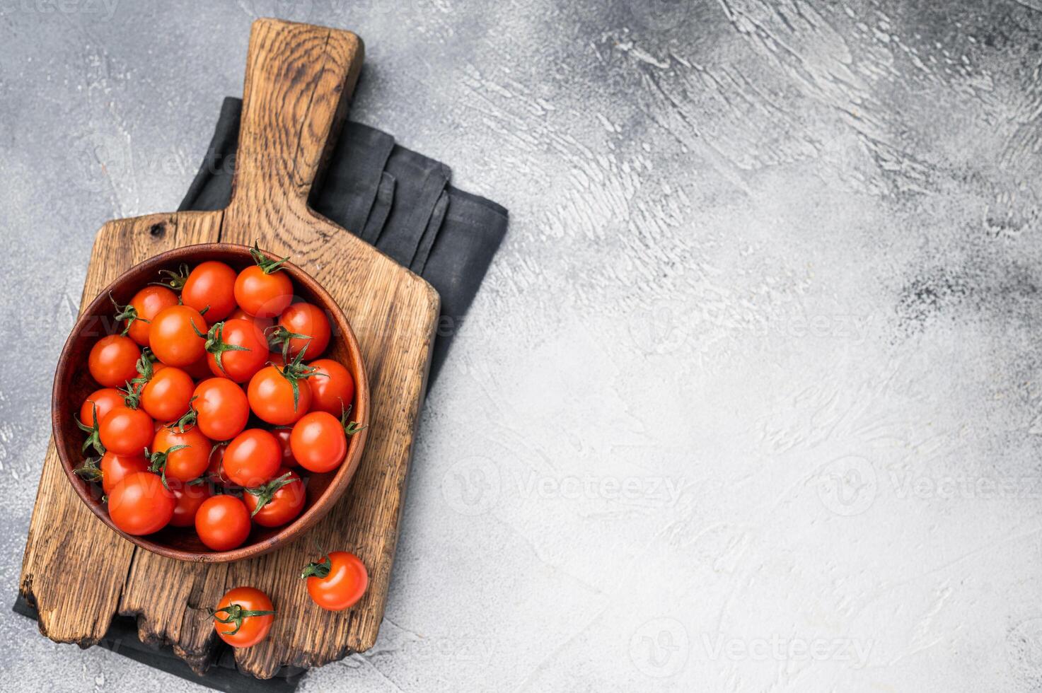 Plump cherry tomatoes, glistening under natural light, highlighting their freshness. Perfect for adding a burst of flavor to any recipe. grey background. top view photo