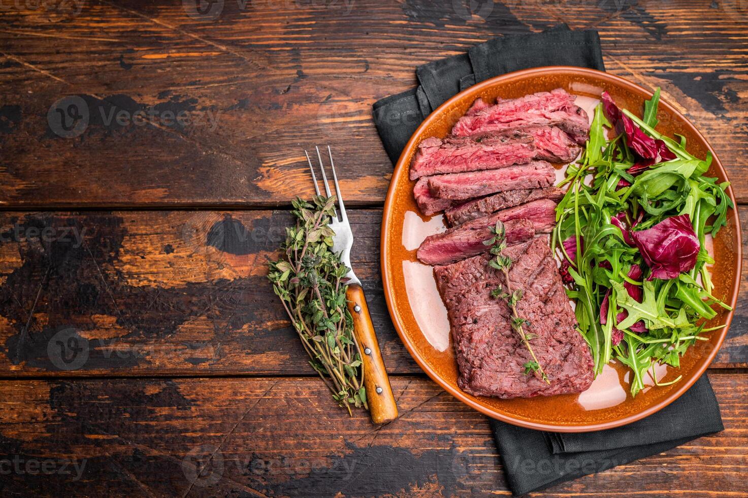 Grilled Skirt machete beef steak, roasted sliced meat on plate with salad. wooden background. top view photo