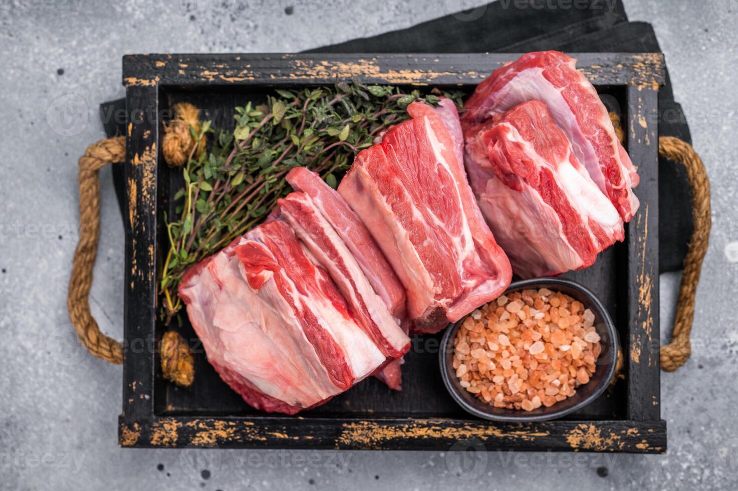 Fresh Raw lamb rib cuts, mutton meat with rib bone in wooden board. grey background. top view photo
