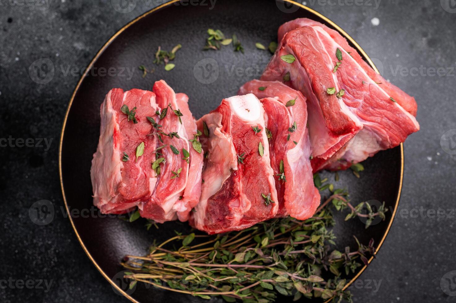 Raw mutton cut rib chops, fresh lamb meat with herbs for grilling. black background. top view photo