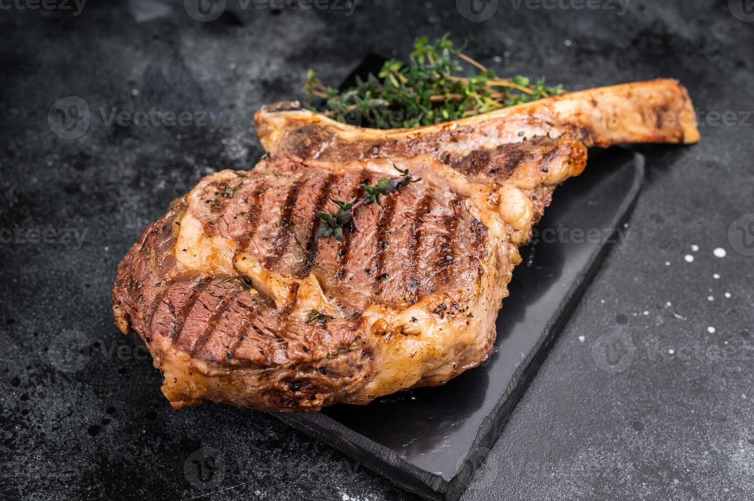 BBQ Grilled Tomahawk beef steak, cooked rib eye with bone on marble board. black background. top view photo