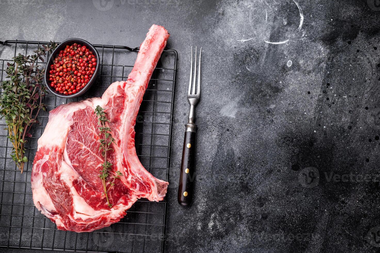 Uncooked tomahawk steak, raw black angus beef rib eye with bone. black background. top view photo