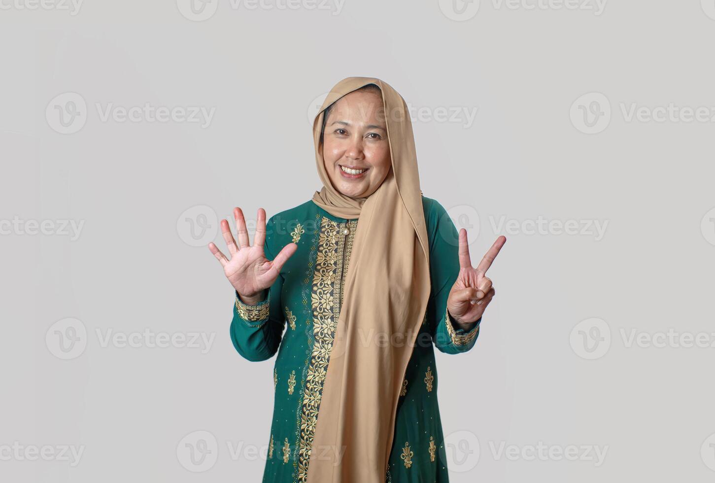 Smiling Woman in Traditional Green Outfit Showing Number Seven Hand Gesture photo