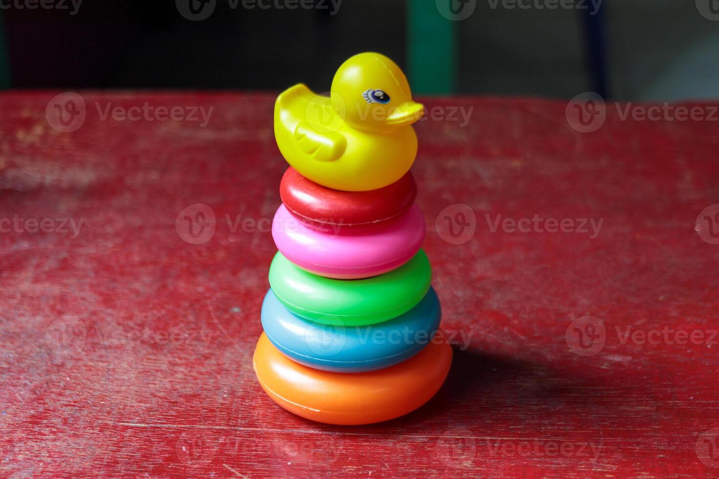 Colorful Stacking Toy with a Yellow Duck on a Red Wooden Surface photo