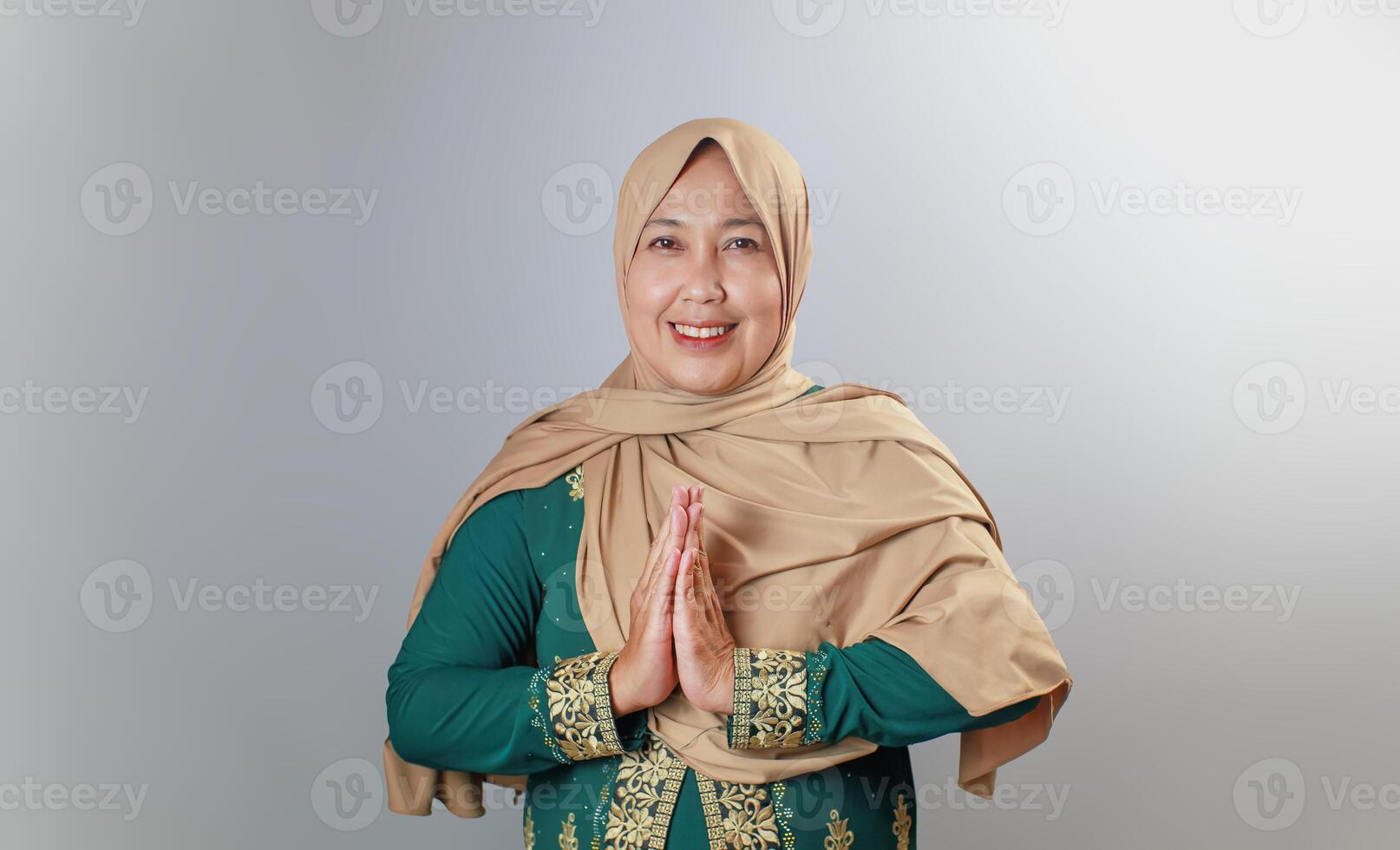 Cheerful Muslim Woman in Elegant Green Dress Giving Greeting Gesture photo