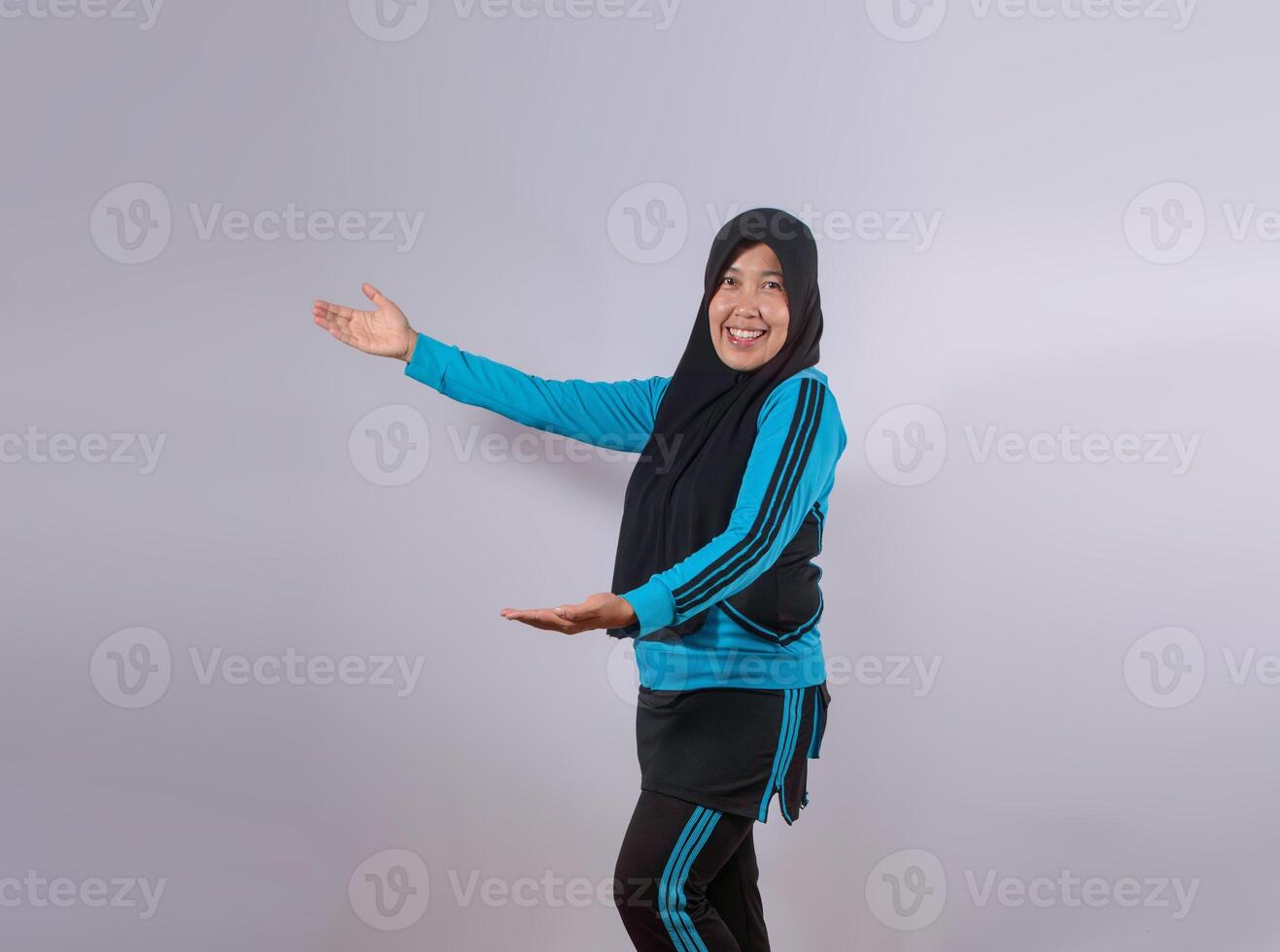 Smiling Muslim Woman in Sportswear Posing with Open Arms on Plain Background photo