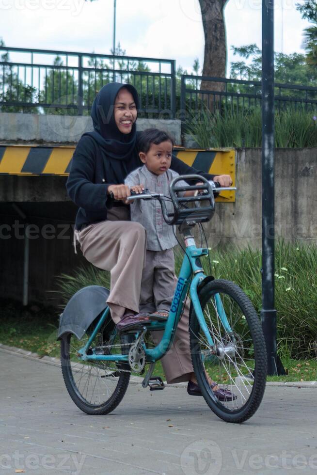 Happy Muslim Woman Riding a Bicycle with Her Child photo