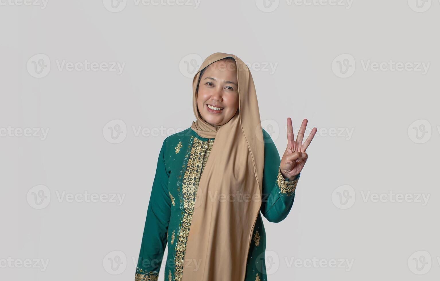 Smiling Woman in Traditional Green Attire Showing Three with Hand Gesture photo