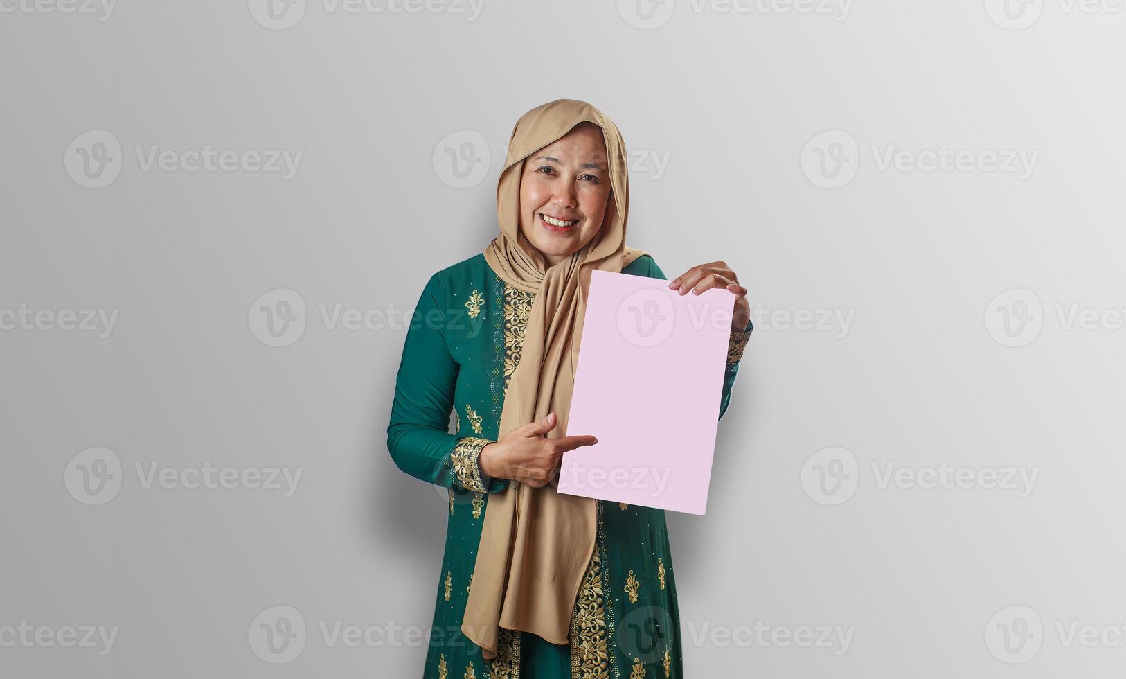 Smiling Muslim Woman Pointing at Pink Paper in Traditional Outfit photo