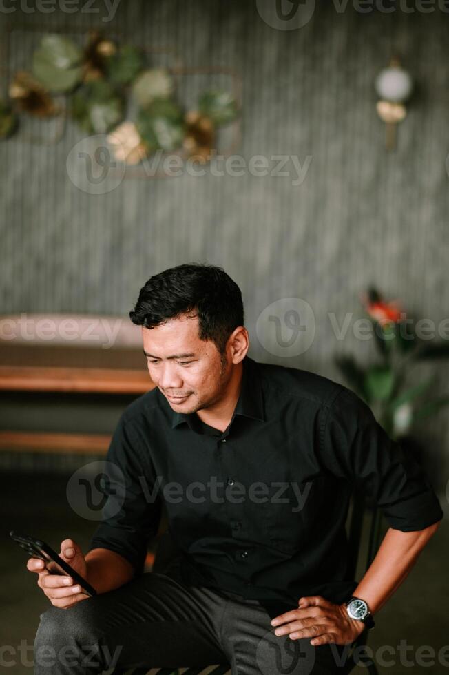 Contented man with phone enjoying modern interior and relaxing indoor photo