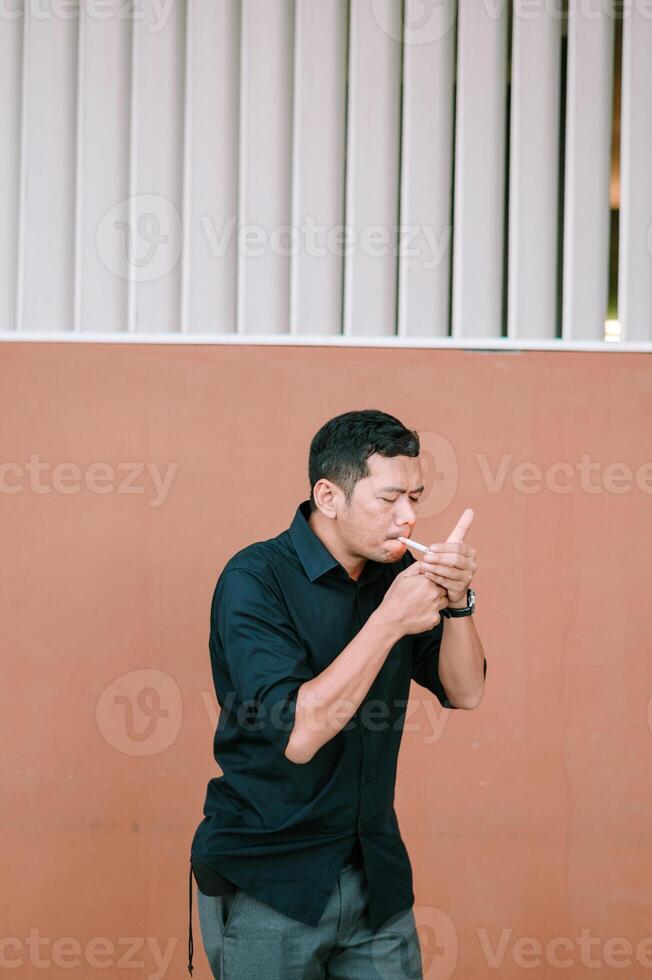 Contemplative man lighting cigarette against modern architectural backdrop photo