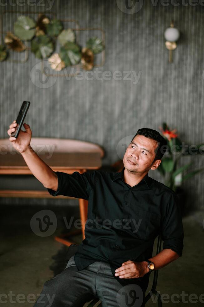 Man captures self portrait with smartphone in decorated lounge area photo