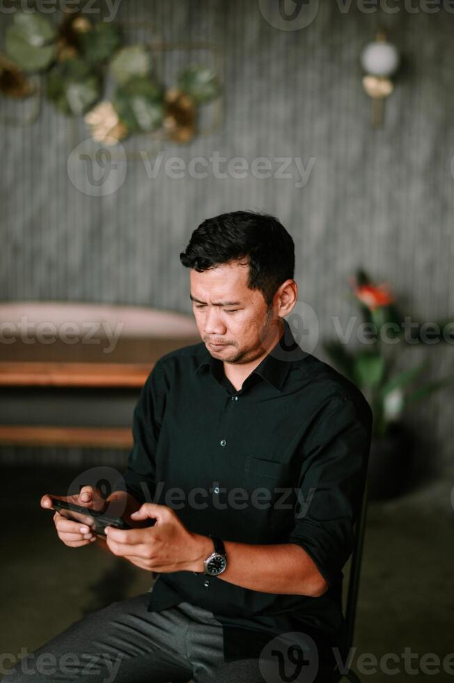 Contemplative man absorbed in his smartphone with modern backdrop photo