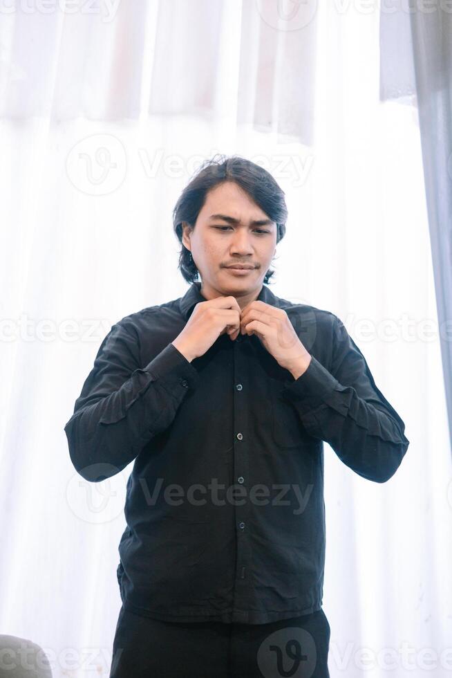 Dressing up , Man prepares for event in all black attire at window photo