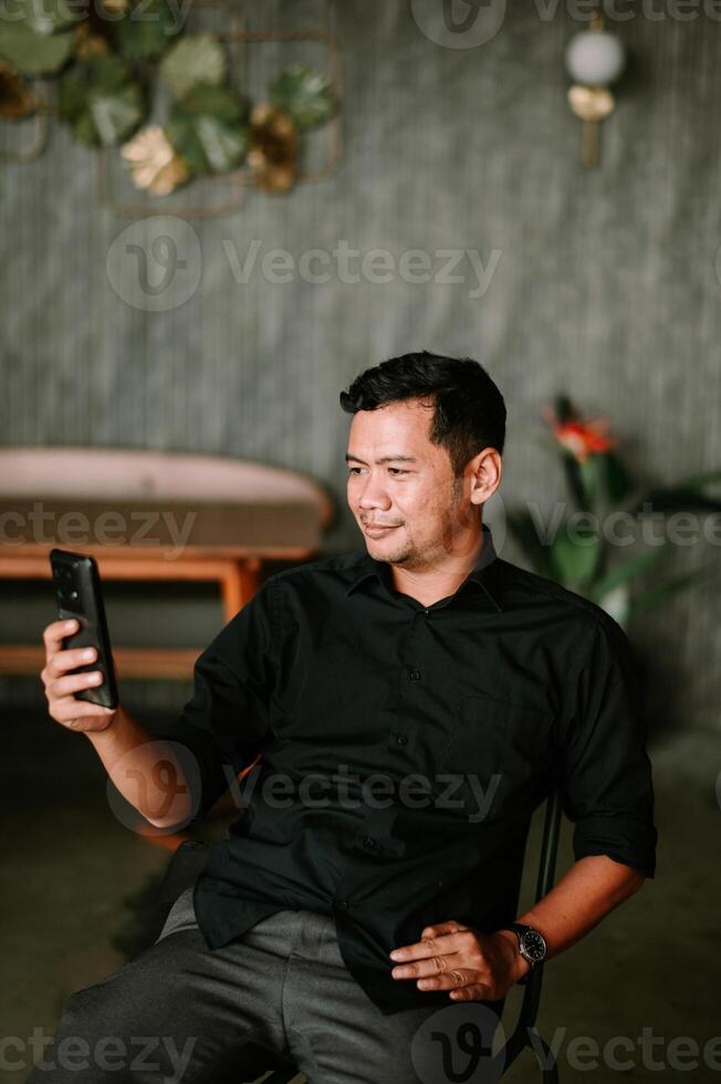 Relaxed asian man enjoys leisure time with his smartphone indoors serenity photo