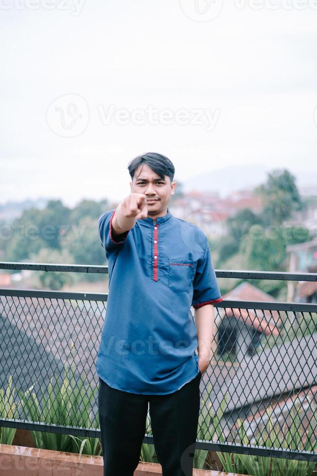 Man pointing towards camera wearing traditional Indonesian clothing photo