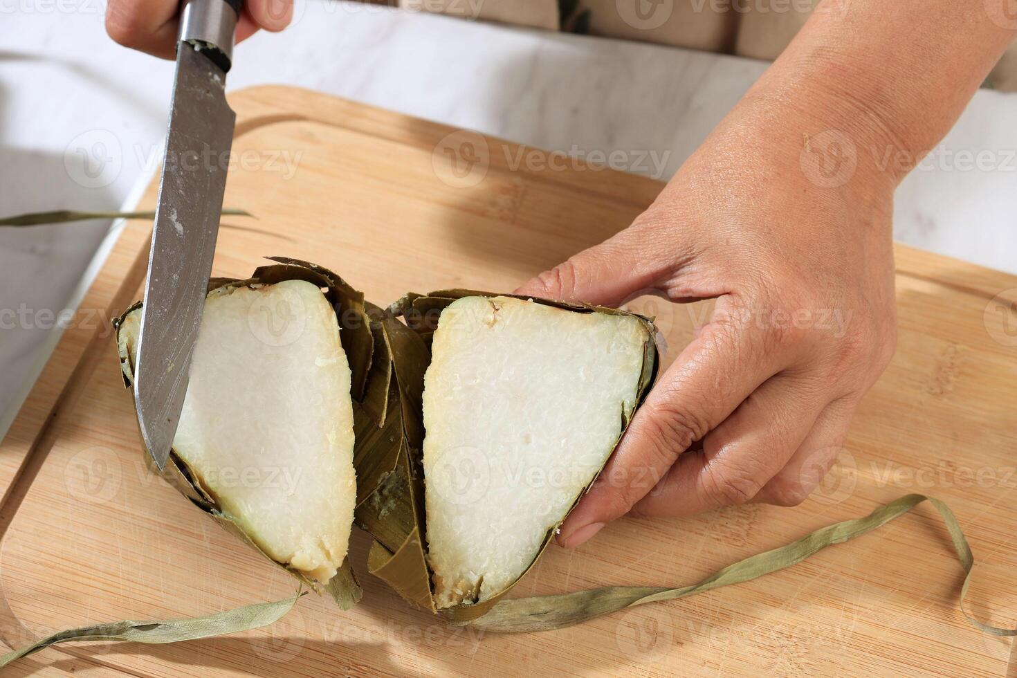 Female Hand Cutting ketupat into Half, Ketupat is Rice Cake with Diamond Shape photo