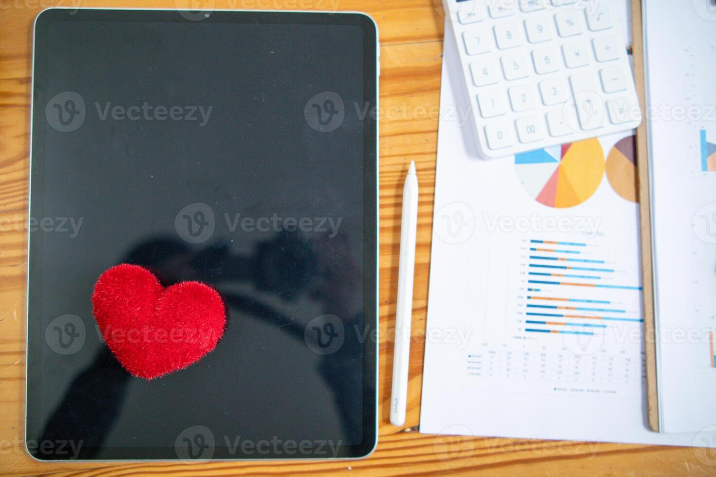 Red heart symbol placed on screen glass of tablet placed on the desk and the heart symbolizes love and friendship for friends and lovers Red heart symbol concept represents friendship and love. photo
