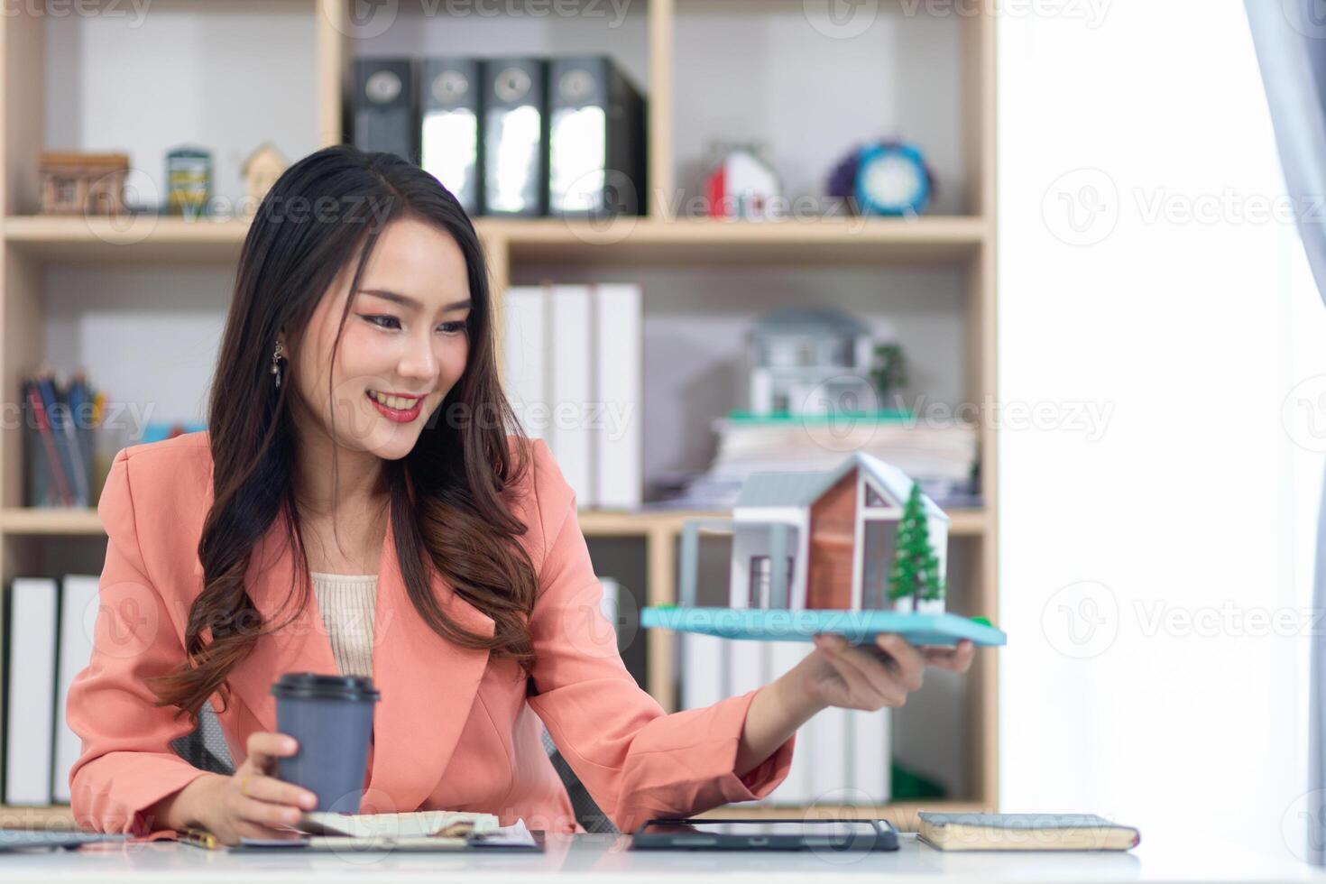 Asian businesswoman is sitting and drinking hot coffee in real estate office because she is real estate agent because the real estate business continues to grow with the increasing population. photo