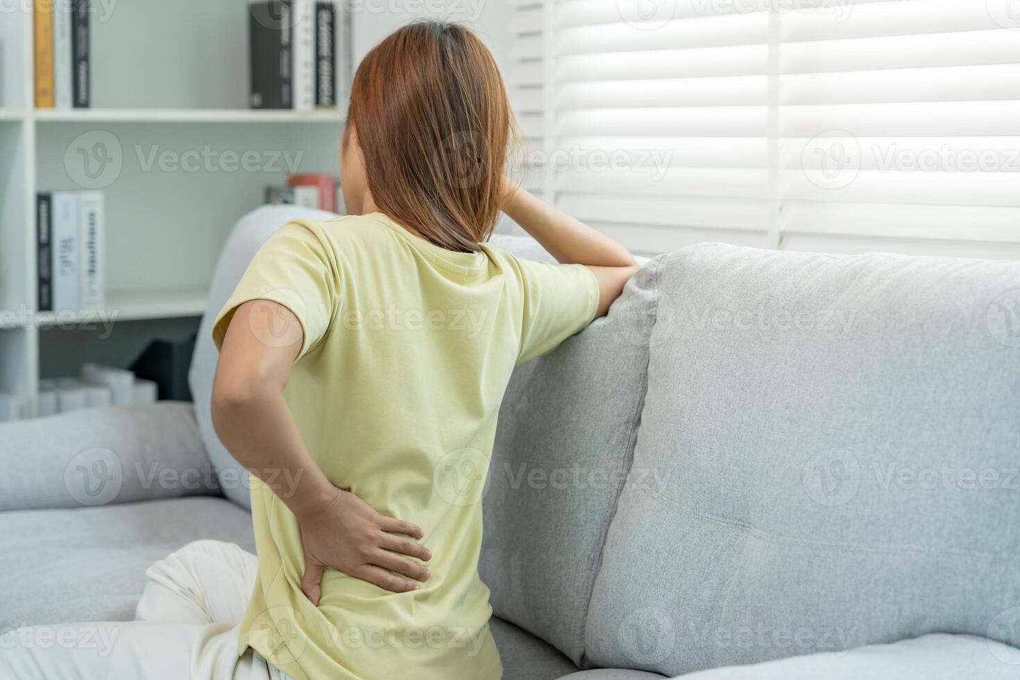 holding her lower back while and suffer from unbearable pain health and problems, chronic back pain, backache in office syndrome, scoliosis, herniated disc, muscle inflammation. photo