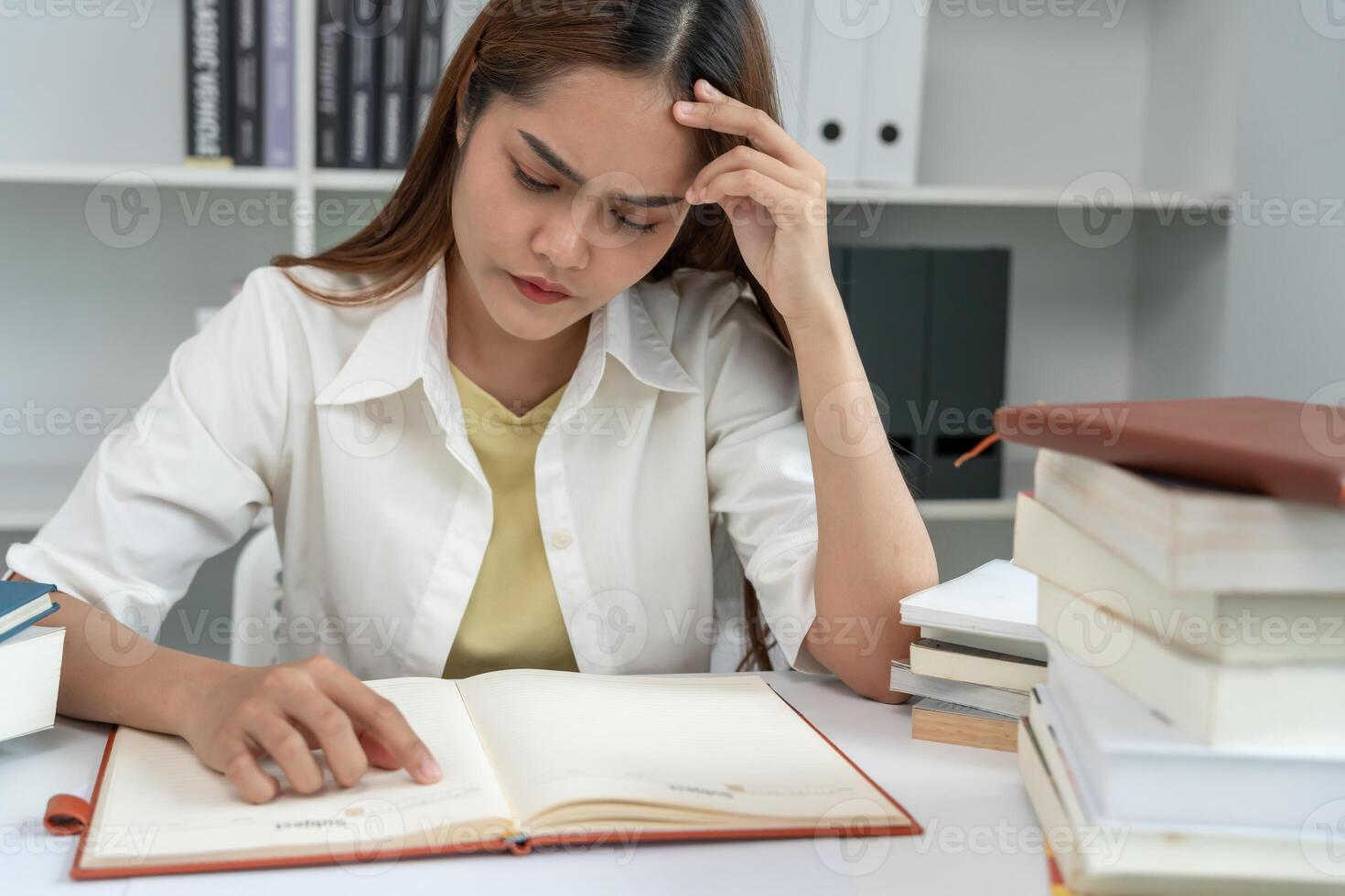Asian student woman have anxiety because of exams, female prepare for test and learning lessons in the library. stress, despair, haste, misunderstanding reading, discouraged, expectation photo