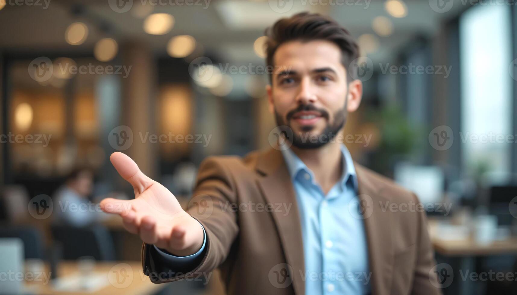 Blurred brunette businessman wear brown blazer in open palm hand, a hand reaching out, Half-body shot, Focus image on hand, Blurred office room background photo