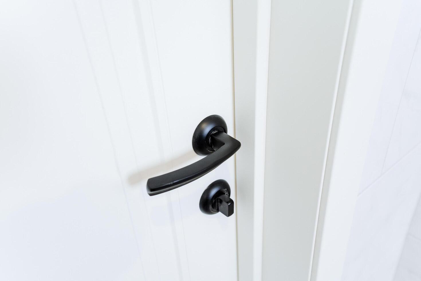 close up of black handle on a white door photo