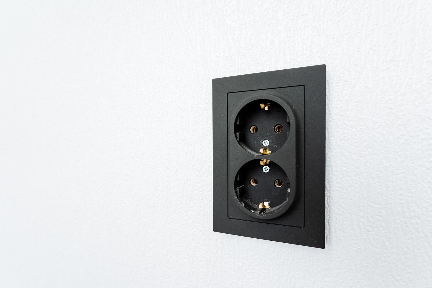 An electrical outlet with two sockets on the wall photo