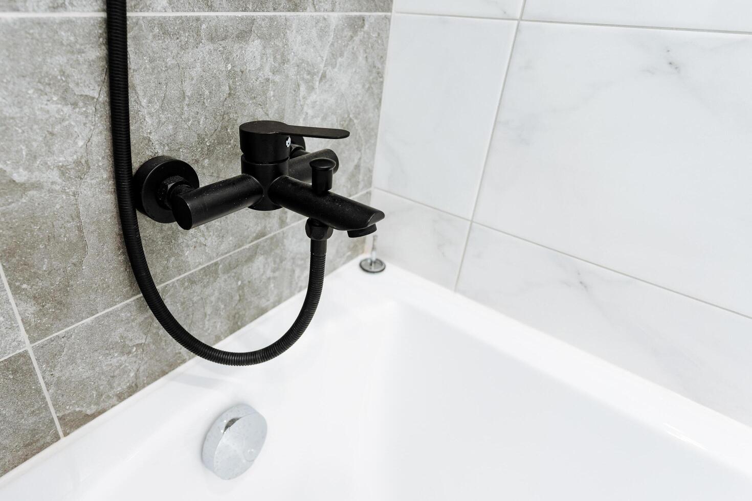 A black shower head is mounted on a wall photo