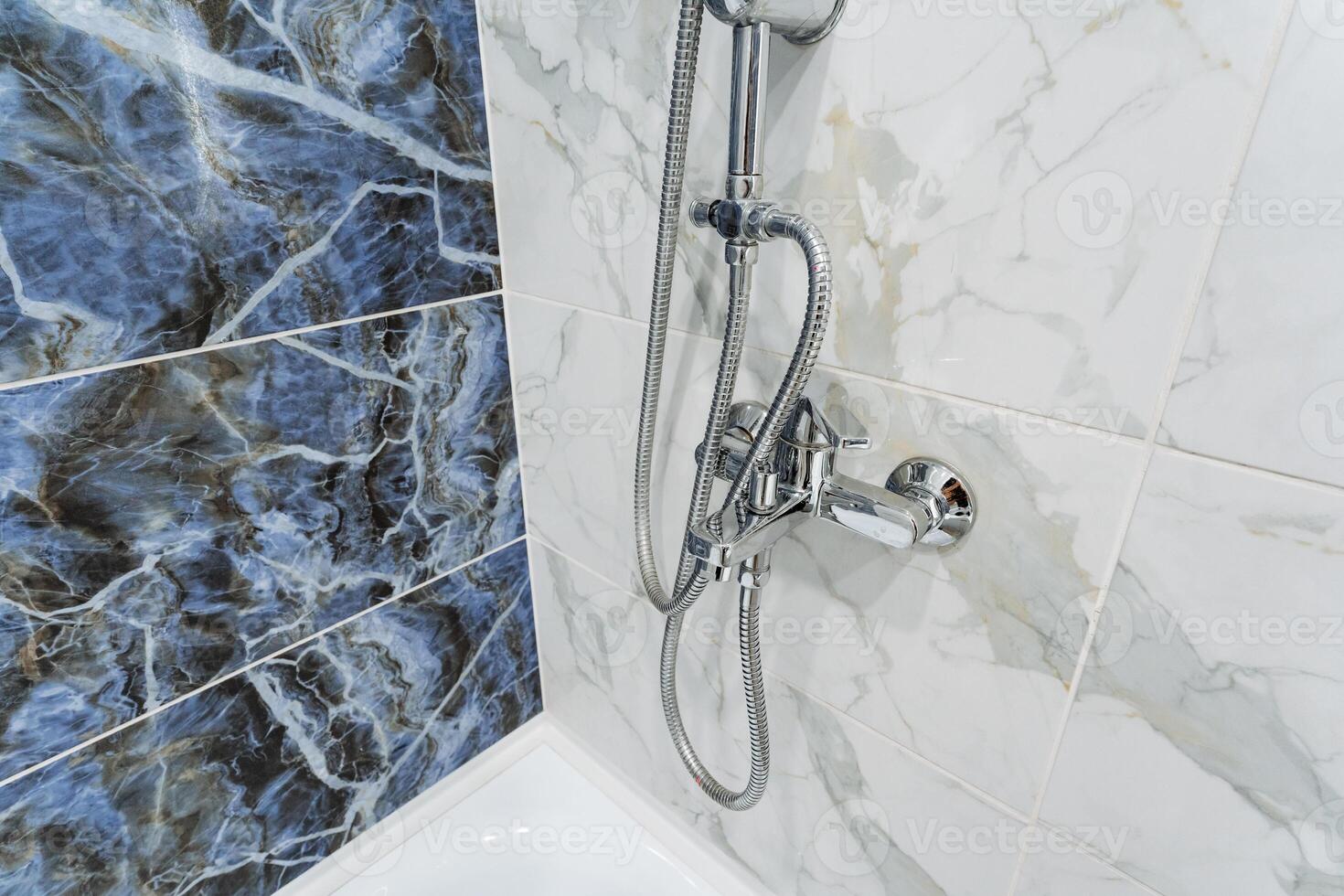 A shower head with a blue marble tile wall photo