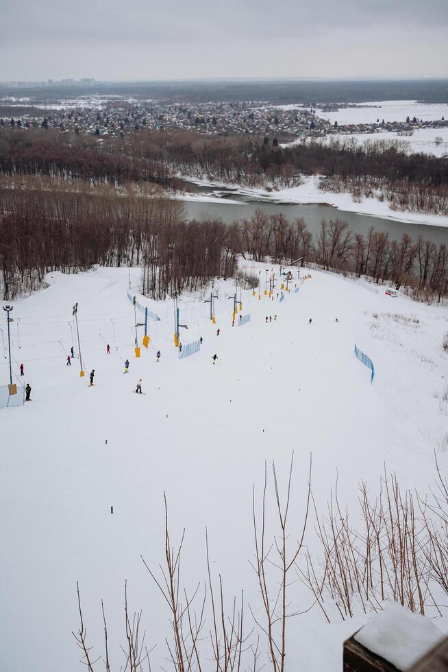 A picturesque and beautiful snowy field stretches endlessly across the landscape, with a serene river flowing gently in the background, creating a breathtaking and tranquil winter scene photo