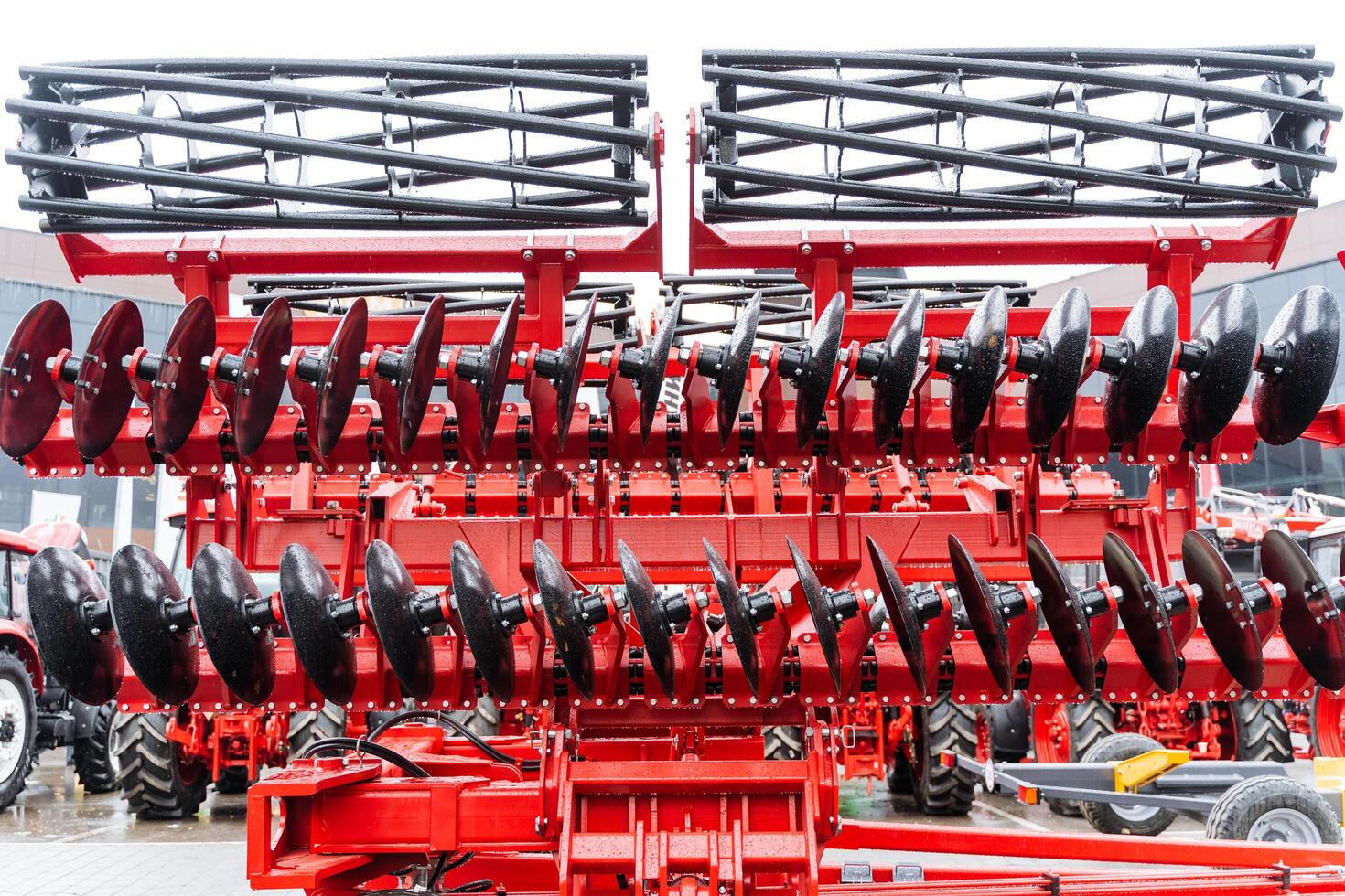 A red tractor with a large disc attached to it photo