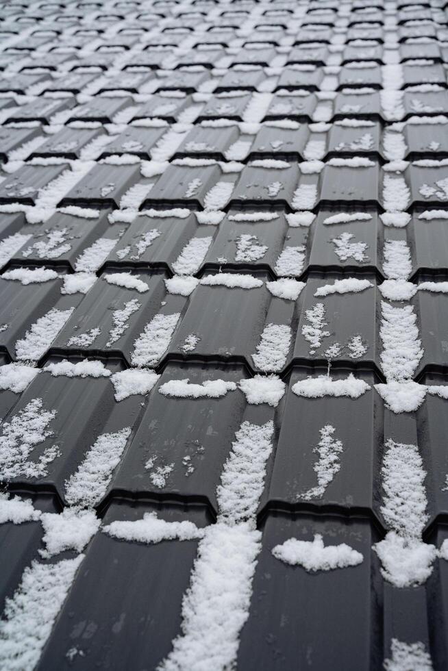 This is a detailed closeup view of a roof that has been covered with a beautiful layer of fresh snow, creating a picturesque winter scene that radiates tranquility and stillness photo