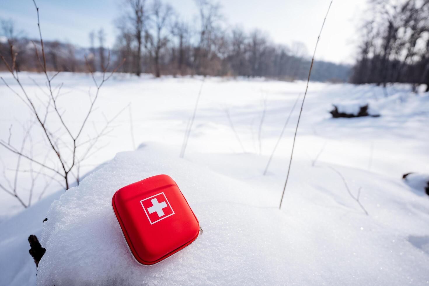red first aid kit laying in the snow winter photo