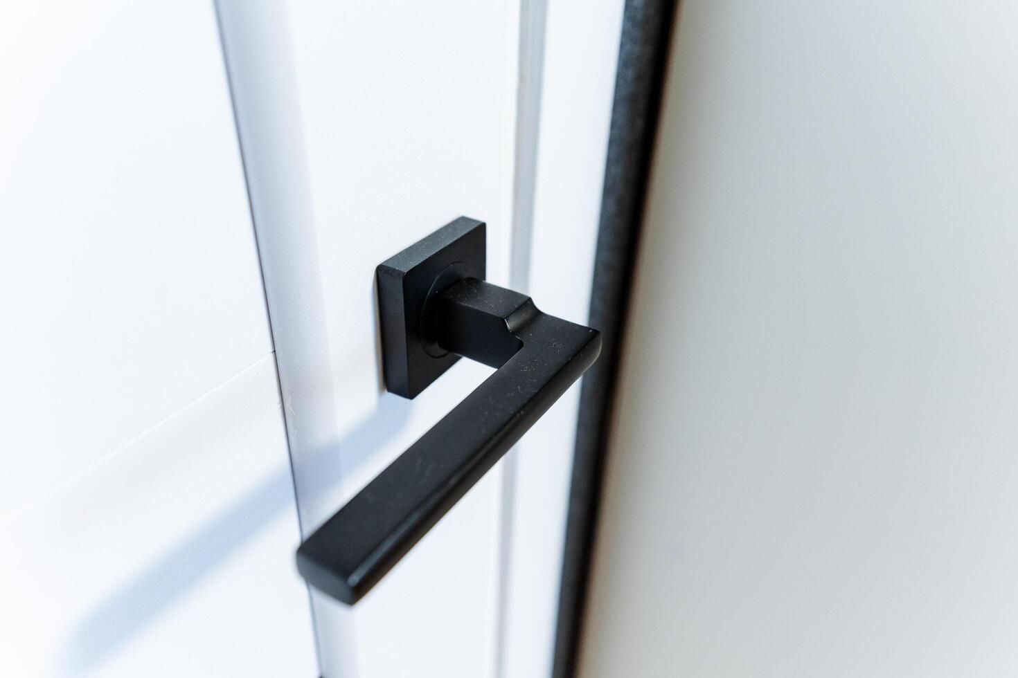 close up of black handle on a white door photo
