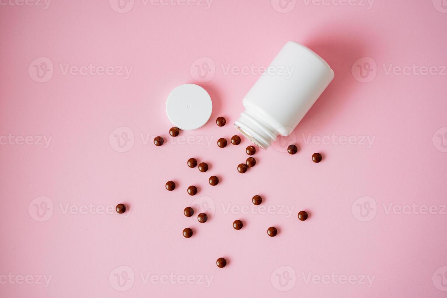 A white bottle filled with various pills is shown pouring them out onto a vibrant pink background, creating a striking visual appeal that highlights the pharmaceutical products inside photo
