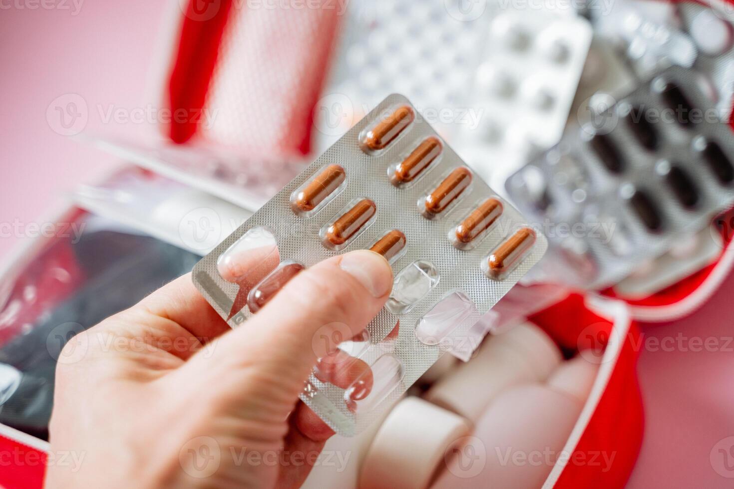 A person has a blister pack of pills held securely in their hand, clearly showing the small compartments that generally contain the medication that is packaged within it safely photo