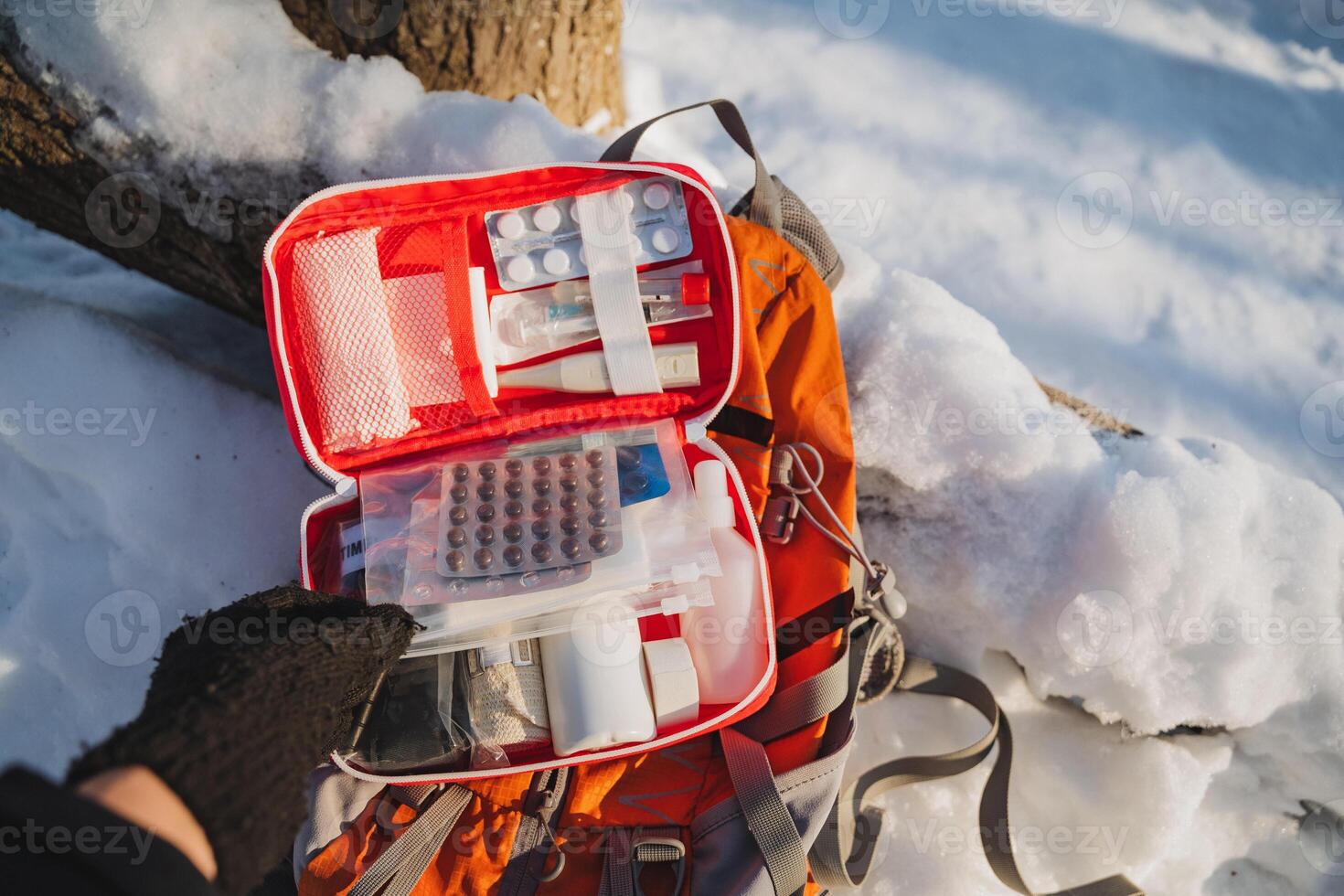 A person is standing in a serene snowy environment, holding a first aid kit, prepared to handle any emergencies that may arise amidst the white snow and picturesque winter scenery photo