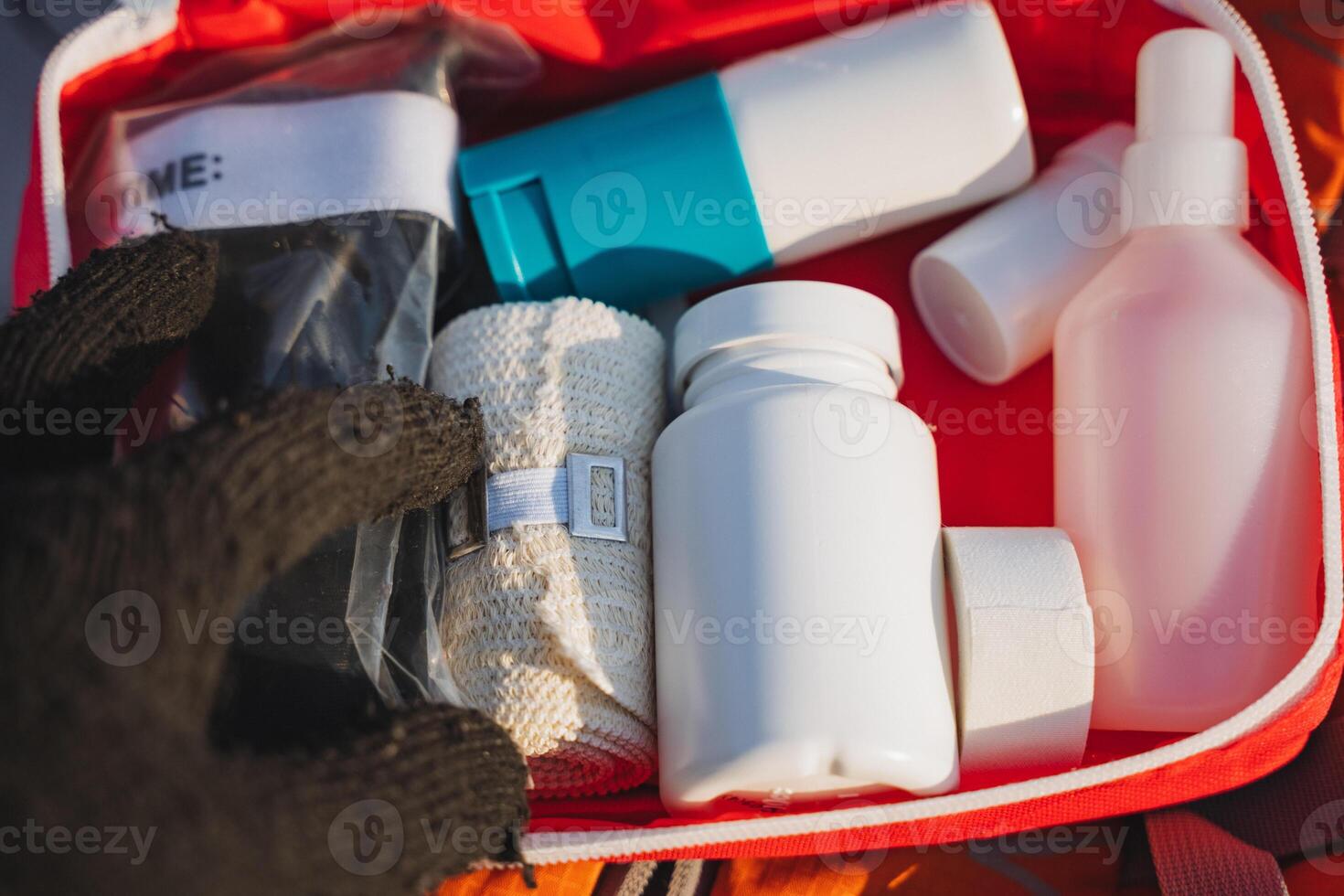 A person is carefully holding a bag filled with various bandages and bottles that are neatly organized inside a wellprepared first aid kit for emergencies or medical situations photo