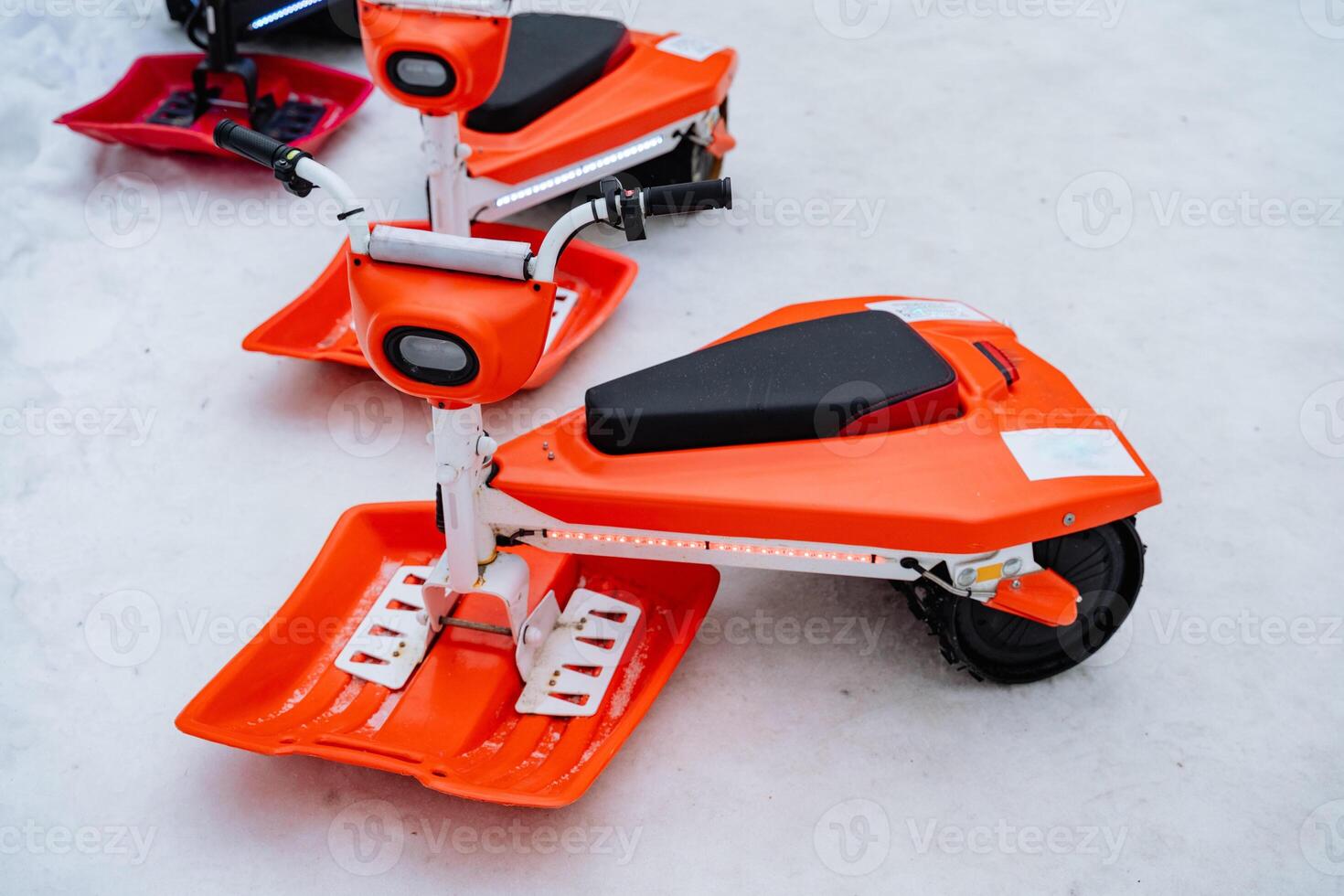 In a beautiful winter scene, you can see two vibrant orange snowmobiles sitting quietly in the freshly fallen snow, highlighting the joy of playtime during the snowy season photo