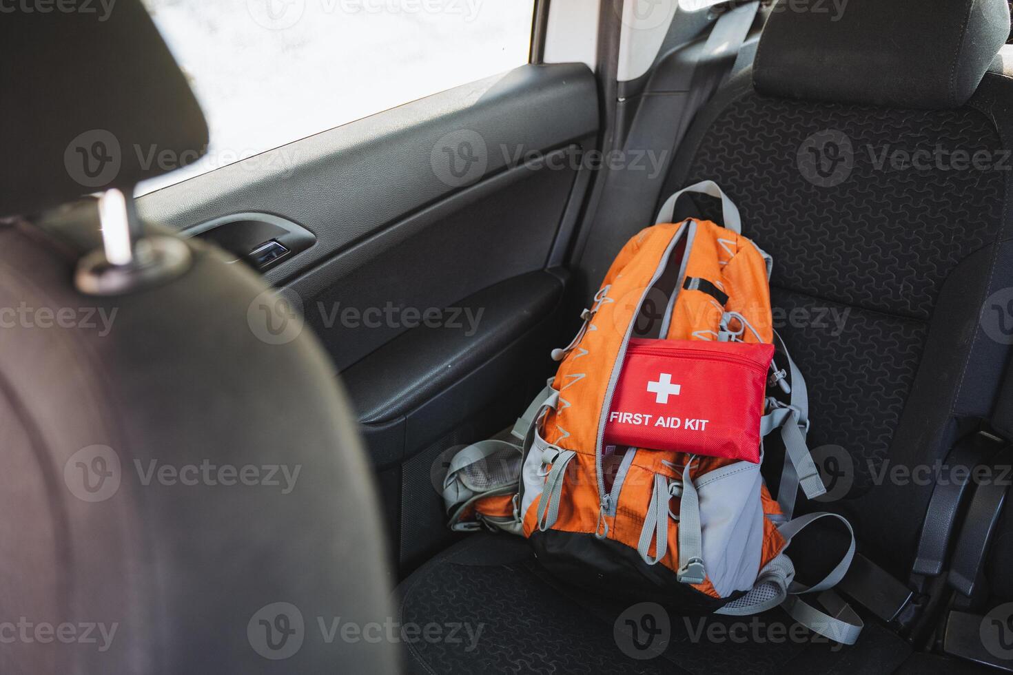 In the back seat of a family car, a wellplaced backpack and a first aid kit are thoughtfully organized for convenient access and ease of use while traveling and going on road trips photo
