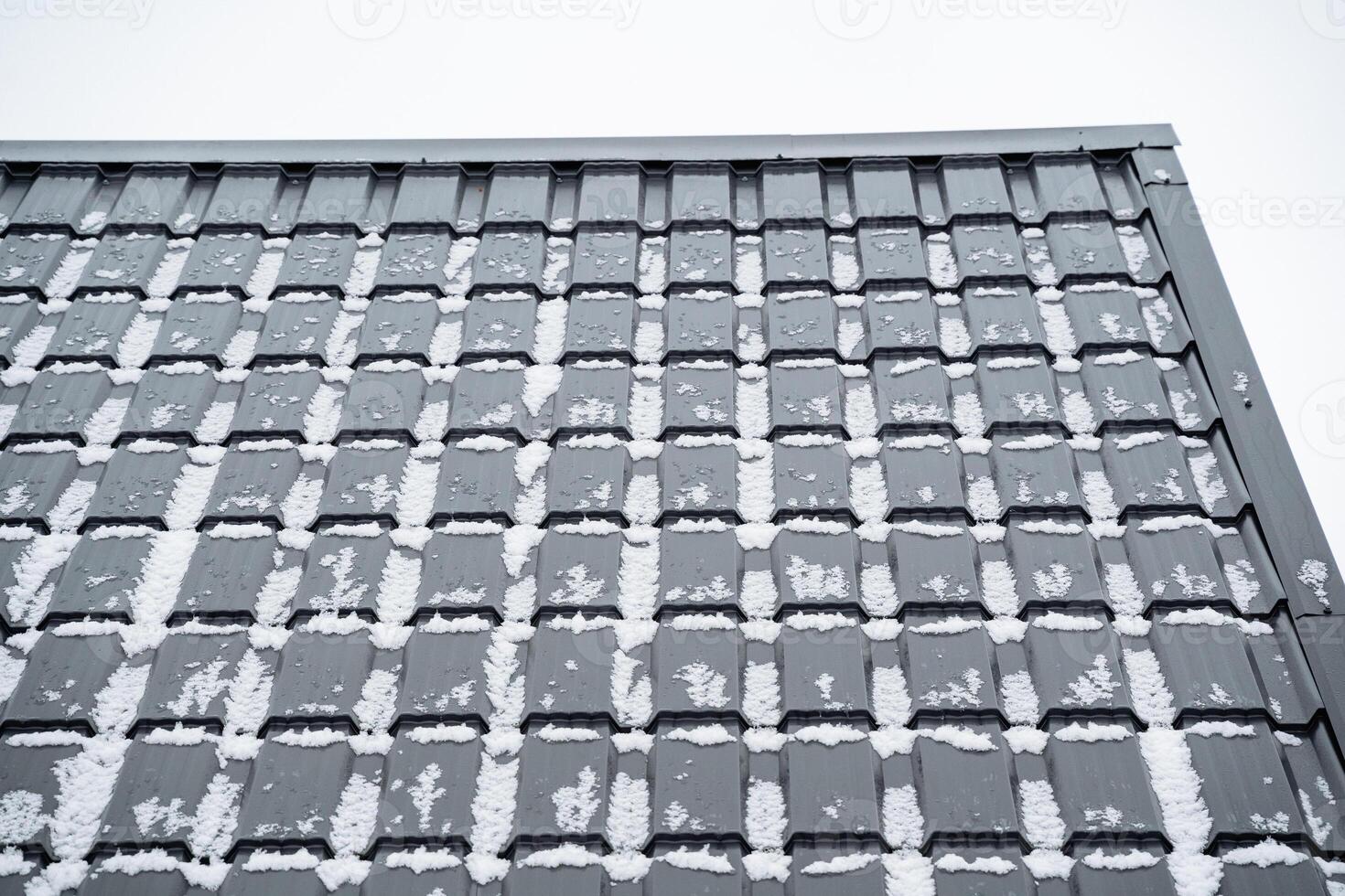 The image features a set of snowcovered roof tiles set against a tranquil winter sky background, bringing out the serenity and beauty of the cold snowy season photo